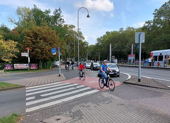Safety first: Rot gefürbte Radwegfurt an einer Hauptverkehrsstraße in Köln
